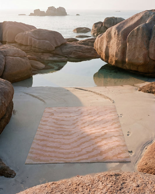 Tapis Agata moiré rose posé sur le sable à marée basse, granit rose de Bretagne, tufté main laine et Tencel Rugier